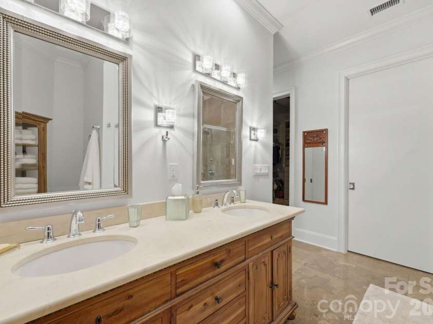 229 Church Street, Charlotte, NC 28202.  MLS# CAR4381312, YatesRealty ID 3818. Luxurious bathroom with dual vanities, natural stone surfaces, custom cabinetry, and elevated lighting that reflects the home’s timeless design.