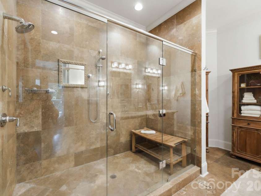 229 Church Street, Charlotte, NC 28202.  MLS# CAR4381312, YatesRealty ID 3818. Spa inspired primary bathroom featuring floor to ceiling natural stone, an oversized glass enclosed shower, and timeless luxury finishes throughout.