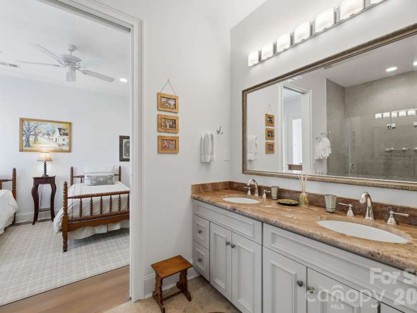 229 Church Street, Charlotte, NC 28202.  MLS# CAR4381312, YatesRealty ID 3818. Well appointed bathroom featuring dual vanities, natural stone surfaces, elevated lighting, and a spacious glass enclosed shower.