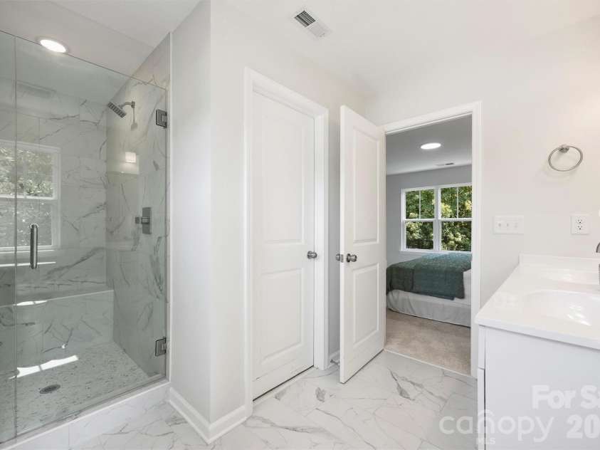 126 Meadow Glen Drive, Troutman, NC 28166.  MLS# CAR4340501, YatesRealty ID 3819. Glass enclosed shower with tiled walls in the primary ensuite.