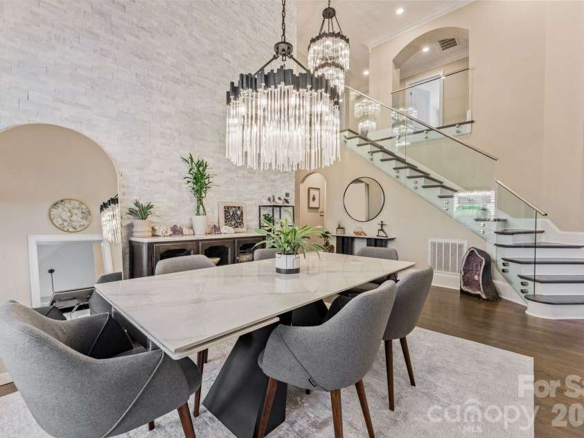 17411 Summer Place Drive, Cornelius, NC 28031.  MLS# CAR4401453, YatesRealty ID 38428. Dining space beneath a tiered crystal chandelier with a dramatic staircase backdrop - seats eight comfortably.