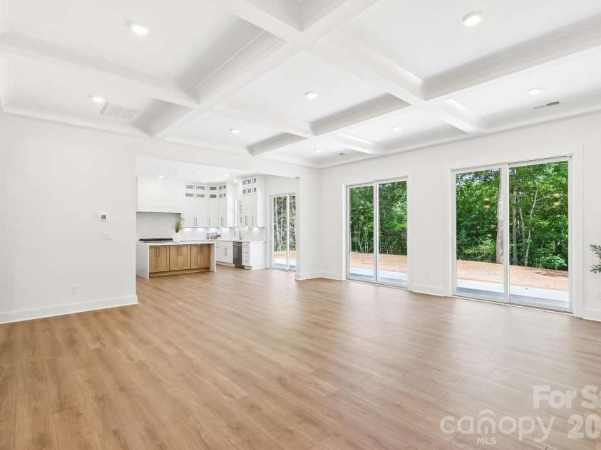 332 Point Carpenter Road, Indian Land, SC 29707.  MLS# CAR4393958, YatesRealty ID 38464. This stunning great room features an open-concept layout that flows seamlessly into the kitchen. The space is bathed in natural light, highlighted by three 8-foot doors that offer picturesque views of the privat