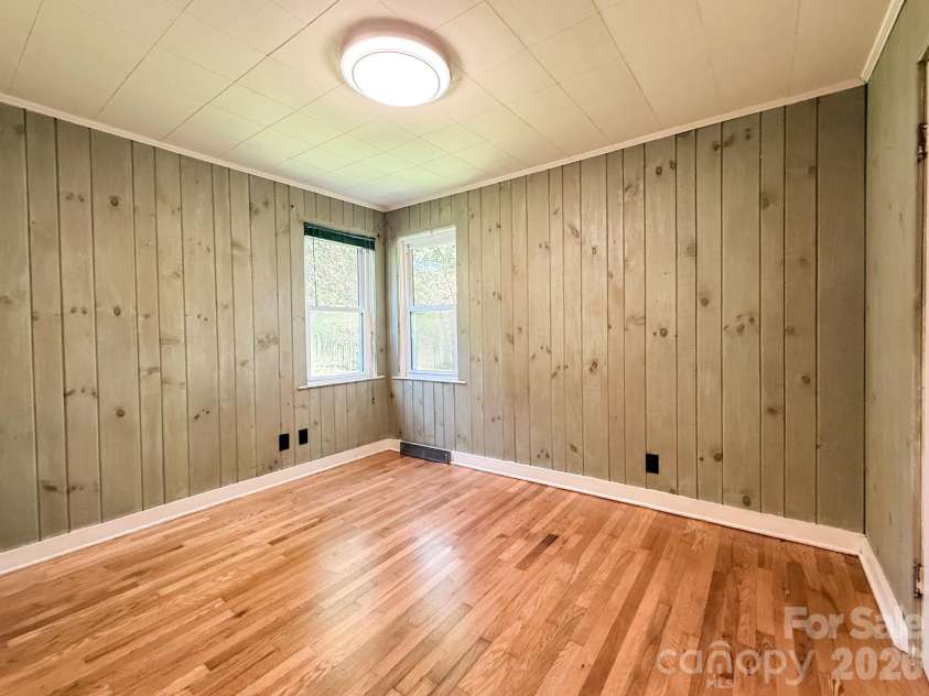 331 Probart Street, Brevard, NC 28712.  MLS# CAR4405723, YatesRealty ID 38535. Second Bedroom – Bright and inviting second bedroom featuring hardwood floors, charming painted wood-paneled walls, and corner windows that bring in abundant natural light.
