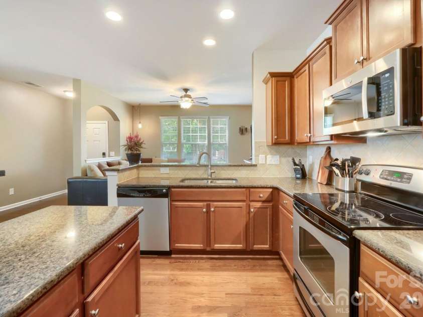13742 Bonnerby Court, Huntersville, NC 28078.  MLS# CAR4392463, YatesRealty ID 38653. A functional kitchen layout with a smooth-top range, deep sink, and tiled backsplash, all framed by warm wood cabinetry.