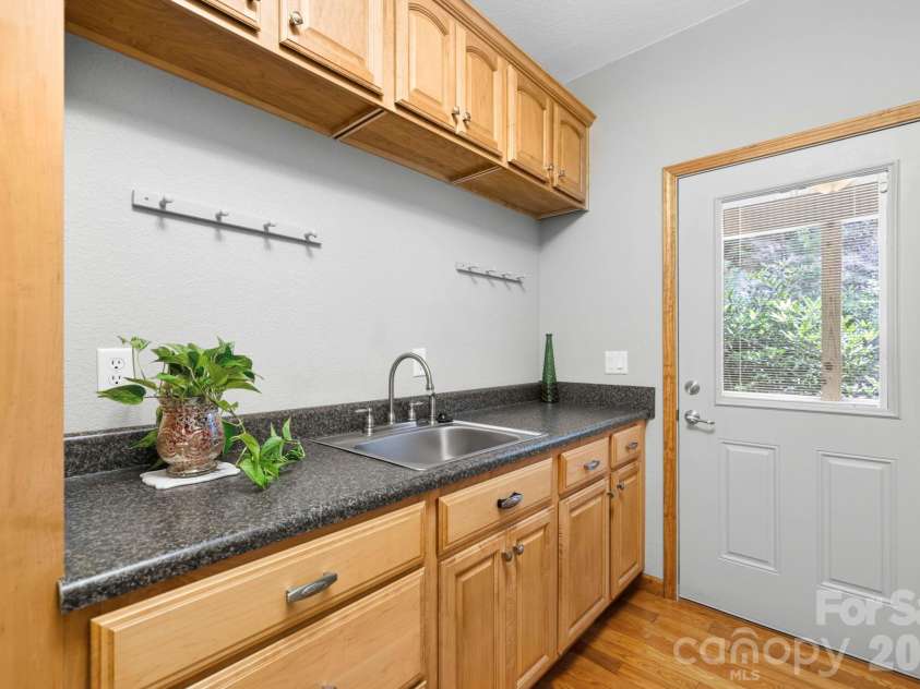 149 Oriole Road, Brevard, NC 28712.  MLS# CAR4404577, YatesRealty ID 38675. Functional laundry room offering generous storage, countertop workspace, utility sink, and convenient outdoor entry.