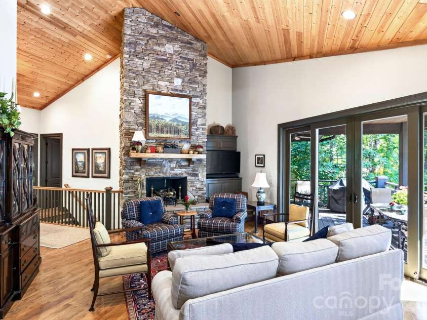 33 Hawks Branch Circle, Fairview, NC 28730.  MLS# CAR4403173, YatesRealty ID 38919. Great room with vaulted wood ceiling, stone fireplace, and deck access