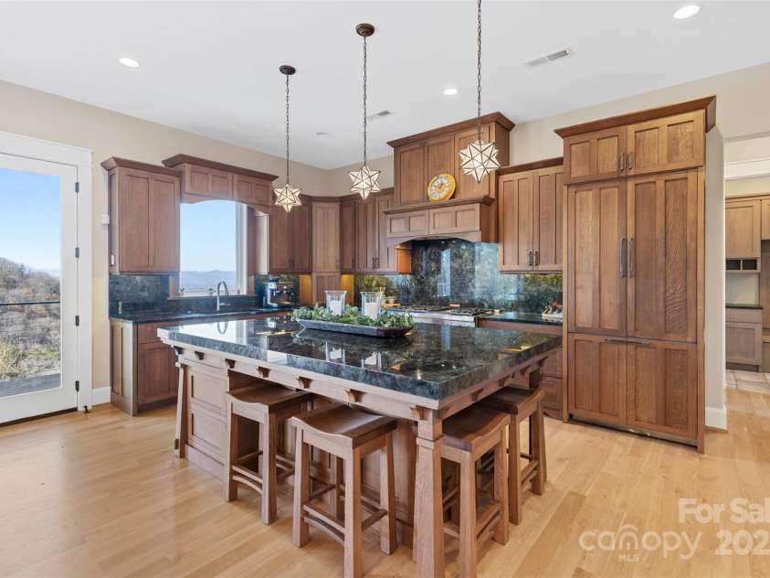 32 Timberwolf Court, Asheville, NC 28804.  MLS# CAR4141057, YatesRealty ID 3907. Thermador Professional appliances paneled to match cabinetry. Solid Labradorite stone countertops and backsplash with iridescent  pops of blues and greens. Large custom-built quarter sawn white oak island with custom st