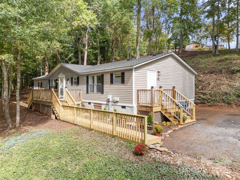 25 Overbrook Drive, Saluda, NC 28773.  MLS# CAR4306681, YatesRealty ID 39133. The house sits on a level area. The yard slopes down in front and up in back. With the partially open and partly wooded property, it creates a nice sense of being removed from surrounding areas. 
