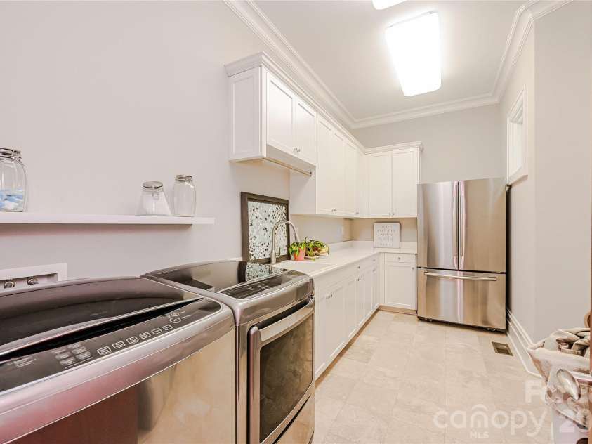 11717 Smart Lane, Charlotte, NC 28277.  MLS# CAR4403907, YatesRealty ID 39154. Large laundry room with sensor lighting, built in upper and lower cabinetry, new deep soaking sink, gas & electric option, built in ironing board, and refrigerator