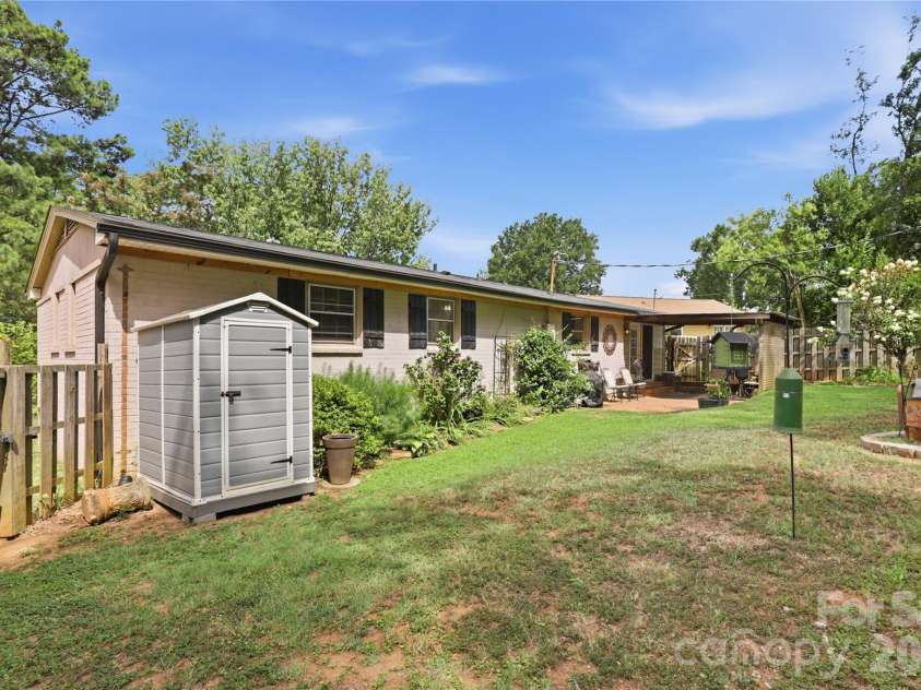 21013 Entrada Drive, Cornelius, NC 28031.  MLS# CAR4402041, YatesRealty ID 39320. Backyard view with patio, landscaping and storage buildings.