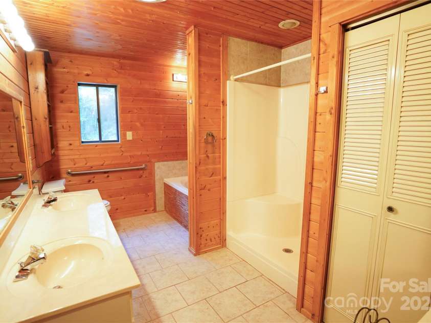 262 Rooster Cove, Brevard, NC 28712.  MLS# CAR4332799, YatesRealty ID 39326. Large bathroom with shower, whirlpool tub, double vanity and large linen closet off of large main level bedroom
