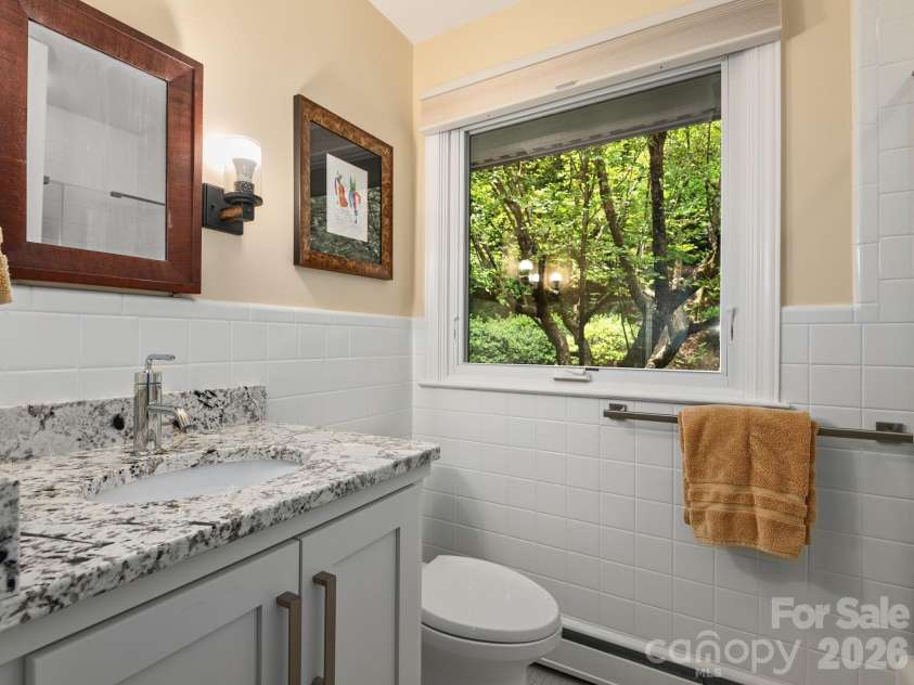 65 Cliff Drive, Laurel Park, NC 28739.  MLS# CAR4394753, YatesRealty ID 39607. Granite countertops, custom cabinetry, and a large window create a bright and inviting main level guest bath