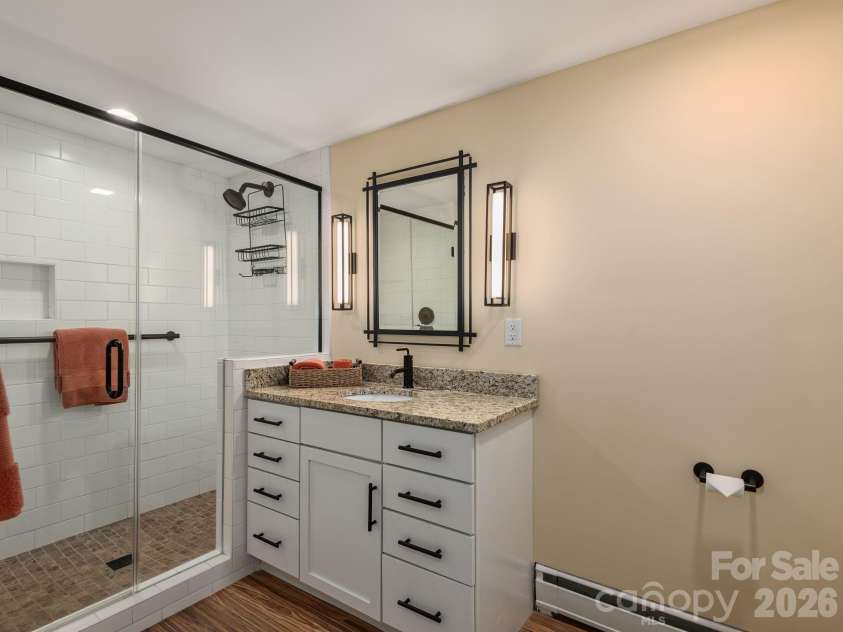 65 Cliff Drive, Laurel Park, NC 28739.  MLS# CAR4394753, YatesRealty ID 39607. The beautifully updated lower-level full bath features a frameless glass walk-in shower, granite countertops, and stylish contemporary finishes