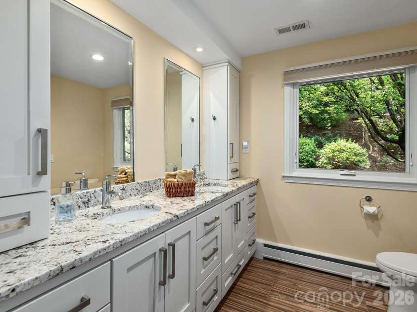 65 Cliff Drive, Laurel Park, NC 28739.  MLS# CAR4394753, YatesRealty ID 39607. The beautifully updated primary bath combines heated tile floors, granite countertops, and custom cabinetry for everyday luxury.