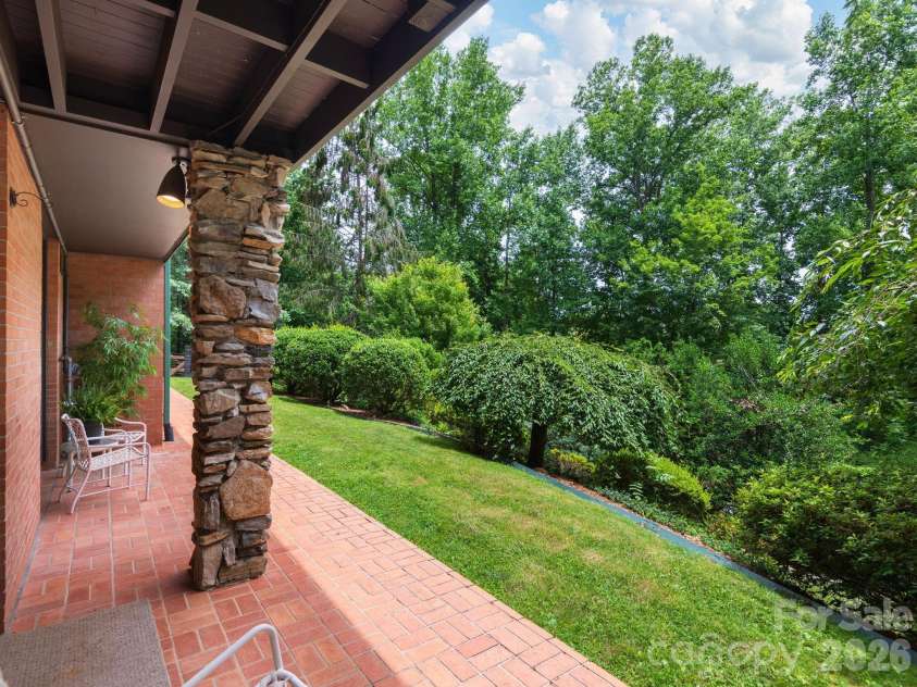 65 Cliff Drive, Laurel Park, NC 28739.  MLS# CAR4394753, YatesRealty ID 39607. The covered lower-level patio opens to a beautifully landscaped, fenced backyard, offering a private outdoor retreat framed by mature trees
