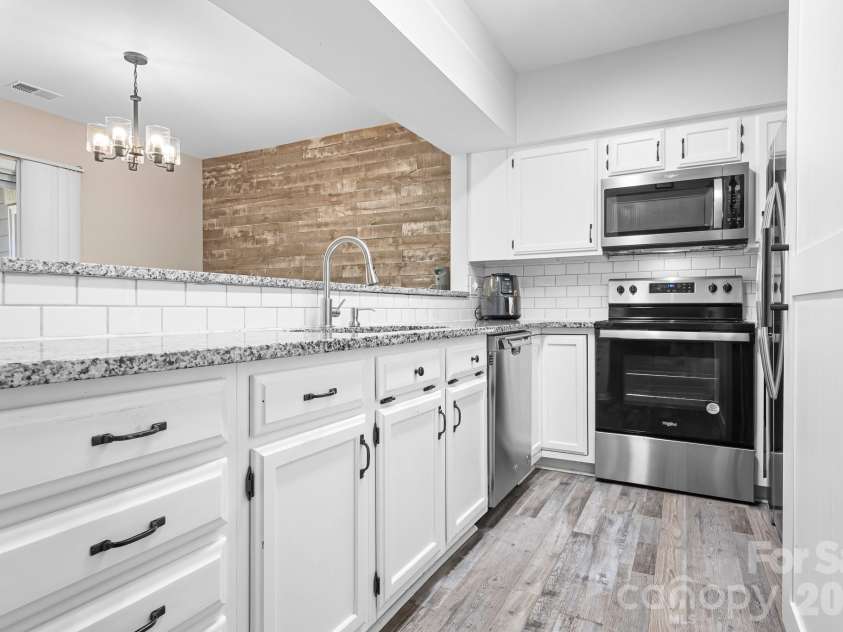 19843 Henderson Road, Cornelius, NC 28031.  MLS# CAR4400549, YatesRealty ID 39667. Galley Kitchen with Full, Long Open Bar Access to the Dining area, Current Finishes, Granite Stainless Steel Wooden Slat Wall in the Dining Area