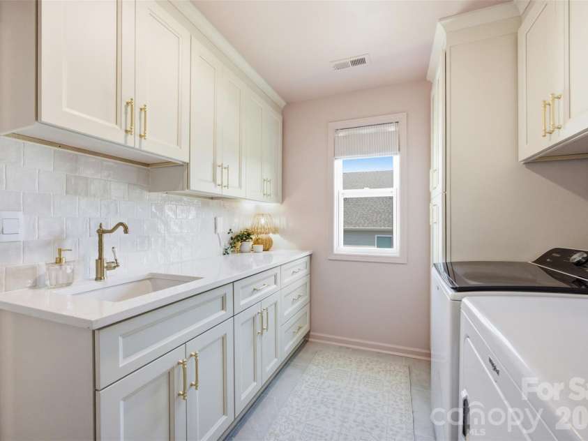 5821 Casper Drive, Charlotte, NC 28214.  MLS# CAR4405553, YatesRealty ID 39797. Gorgeous laundry room with custom cabinets, quartz countertops, tile backsplash, and a sink.