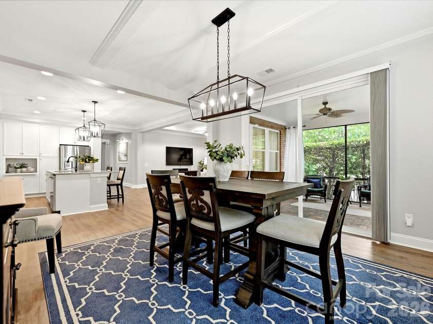 16620 Redding Park Lane, Cornelius, NC 28031.  MLS# CAR4404866, YatesRealty ID 39811. The open dining area is enhanced by large windows, elegant lighting, and direct access to the screened porch, offering a bright and welcoming space for gathering with family and friends.