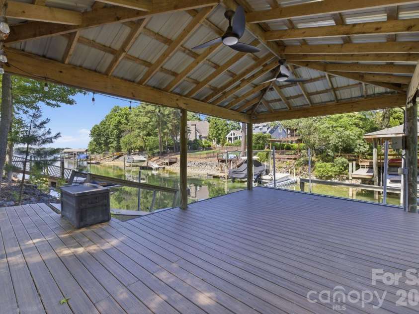 19624 Meta Road, Cornelius, NC 28031.  MLS# CAR4394341, YatesRealty ID 39952. View from the deck toward the covered dock emphasizes the home’s direct waterfront connection. Buyers can immediately picture lake days just steps from the house.