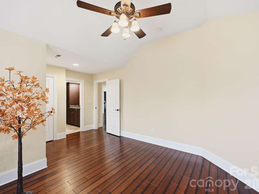108 Washam Road, Mooresville, NC 28117.  MLS# CAR4334255, YatesRealty ID 4048. BR 2 Bright and spacious bedroom featuring hardwood floors, a ceiling fan with light fixture, and neutral walls that create a clean, open feel. The room offers a simple layout with easy access to the adjoining hallway and