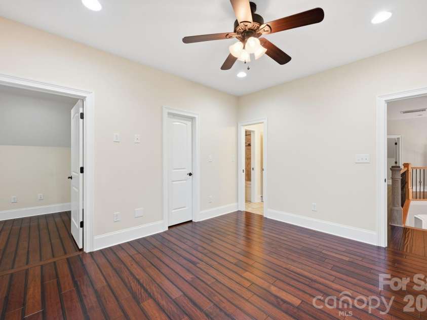 108 Washam Road, Mooresville, NC 28117.  MLS# CAR4334255, YatesRealty ID 4048. BR 3 Bright and open bedroom or flex space featuring rich hardwood floors, neutral paint, recessed lighting, and a ceiling fan with light fixture. The room offers multiple access points and a clean, versatile layout ideal
