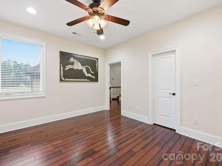 108 Washam Road, Mooresville, NC 28117.  MLS# CAR4334255, YatesRealty ID 4048. Bright and spacious bedroom featuring hardwood floors, neutral walls, and a ceiling fan with light fixture. The room offers natural light from a large window and a clean, open layout suitable for a guest room, office, or 
