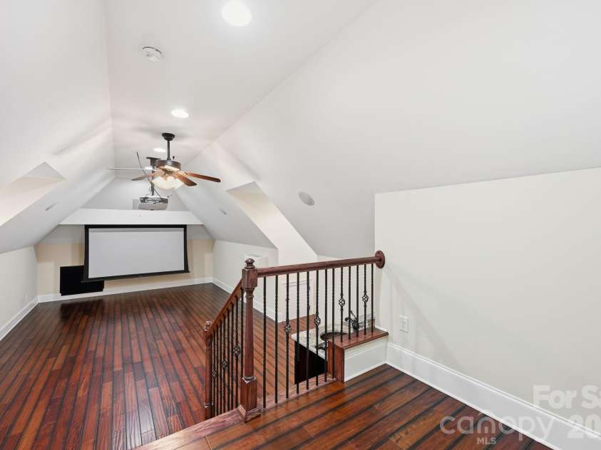 108 Washam Road, Mooresville, NC 28117.  MLS# CAR4334255, YatesRealty ID 4048. Bright upper level loft or theater room with vaulted ceilings, hardwood floors, and recessed lighting. Open railing overlooks the main living space, creating an airy feel ideal for a flex room, office, or additional sitti
