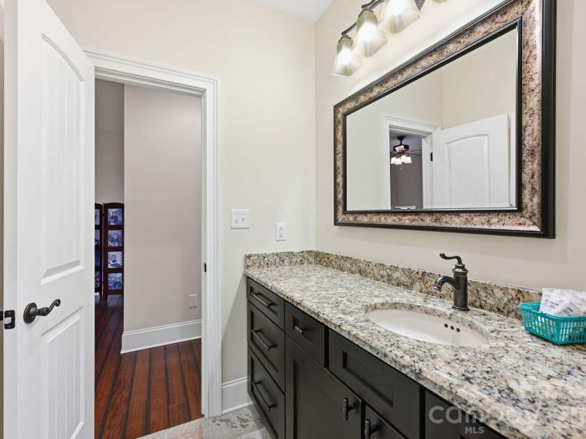 108 Washam Road, Mooresville, NC 28117.  MLS# CAR4334255, YatesRealty ID 4048. Clean and well-appointed bathroom featuring a granite vanity countertop, dark wood cabinetry, framed mirror, and modern lighting. Neutral tones and a functional layout create a bright, inviting space with easy access to t