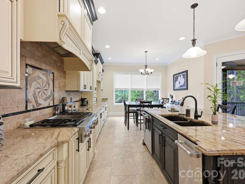 108 Washam Road, Mooresville, NC 28117.  MLS# CAR4334255, YatesRealty ID 4048. Spacious, gourmet kitchen with custom cabinetry, granite countertops, and a large center island with sink and seating. The space features stainless steel appliances, decorative tile backsplash, pendant lighting, and an op