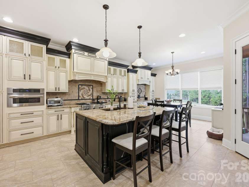 108 Washam Road, Mooresville, NC 28117.  MLS# CAR4334255, YatesRealty ID 4048. Spacious, well-appointed kitchen featuring custom cabinetry, a large center island with seating, and granite countertops. The room is filled with natural light and includes pendant lighting, tile flooring, and an open lay
