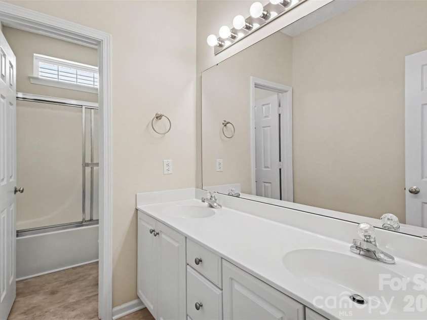 576 Gatsby Place, Concord, NC 28027.  MLS# CAR4403002, YatesRealty ID 40800. Second full bathroom featuring dual vanities, white cabinetry with ample storage, and a separate room for the water closet and tub/shower. Brand new flooring has just been installed.