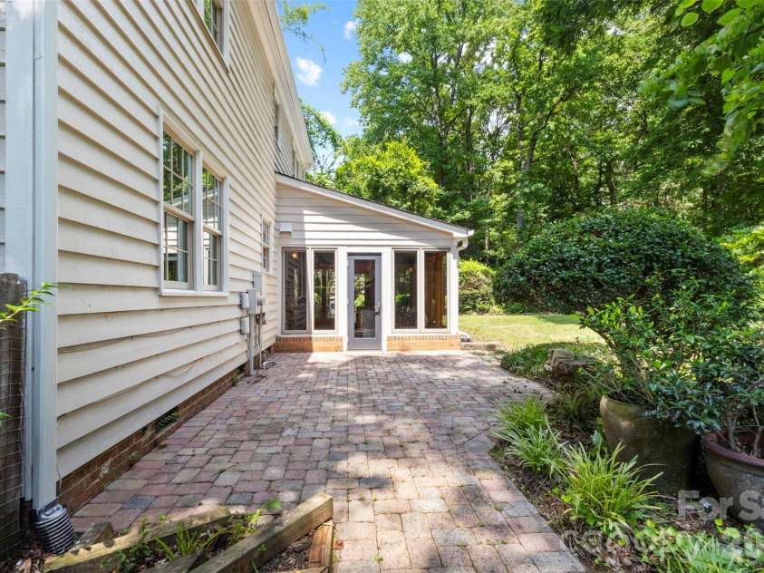 7721 Bradenton Drive, Charlotte, NC 28210.  MLS# CAR4408258, YatesRealty ID 41159. Side Exterior – Side walkway leading to the backyard and sunroom, bordered by established landscaping and mature trees.
