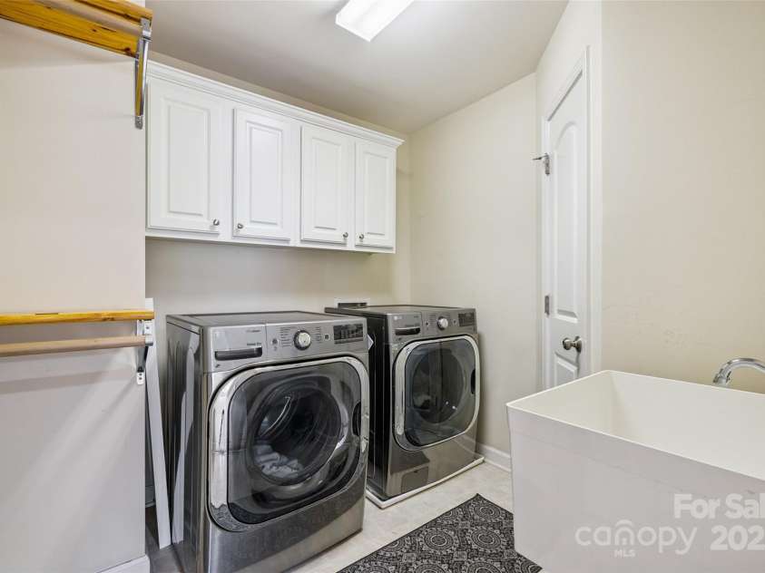 9142 Drayton Lane, Indian Land, SC 29707.  MLS# CAR4275785, YatesRealty ID 417. Laundry room has a utility sink, cabinets, and built in hanging racks, along with a closet access to the Primary bathroom