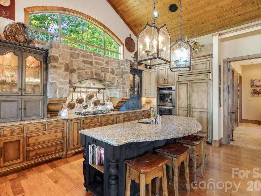 817 Running Cedar Lane, Mars Hill, NC 28754.  MLS# CAR4407984, YatesRealty ID 42073. A dramatic stone cooking alcove anchors the kitchen, while soaring wood ceilings, arched windows and oversized lantern pendants beautifully express the home’s refined French Country character.