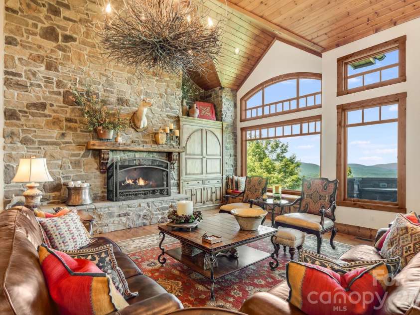817 Running Cedar Lane, Mars Hill, NC 28754.  MLS# CAR4407984, YatesRealty ID 42073. A magnificent floor to ceiling stone fireplace anchors the great room, while soaring arched windows, warm wood ceilings and a sculptural branch chandelier frame the home’s breathtaking Blue Ridge Mountain views.