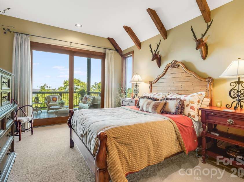 817 Running Cedar Lane, Mars Hill, NC 28754.  MLS# CAR4407984, YatesRealty ID 42073. Bedroom 3 features a vaulted ceiling with exposed timber beams, a beautiful ensuite bath and double doors leading directly to the covered deck seating area.