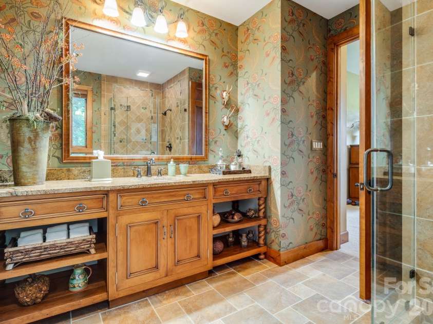 817 Running Cedar Lane, Mars Hill, NC 28754.  MLS# CAR4407984, YatesRealty ID 42073. The beautifully appointed ensuite bath features custom cabinetry, a granite topped vanity, warm wood accents and an oversized glass enclosed shower.