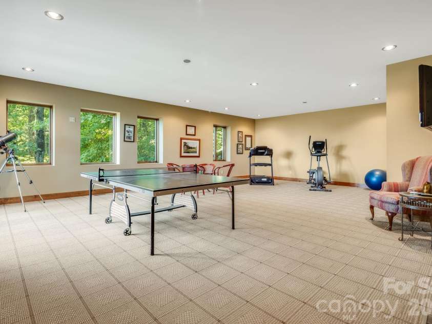 817 Running Cedar Lane, Mars Hill, NC 28754.  MLS# CAR4407984, YatesRealty ID 42073. This expansive recreation room provides space for table tennis, indoor workouts and relaxed gatherings, with abundant natural light and peaceful wooded views.
