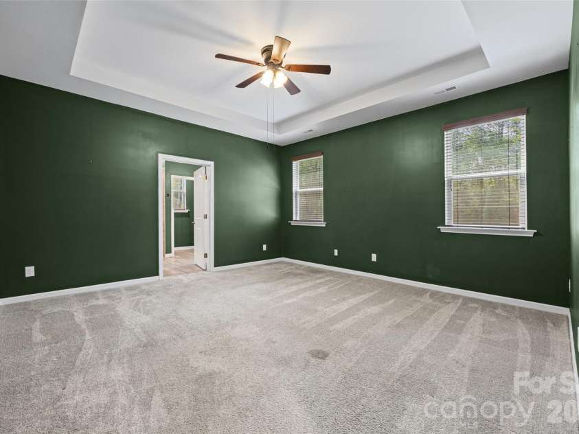 596 Rustlewood Way, Rock Hill, SC 29732.  MLS# CAR4409855, YatesRealty ID 42174. Spacious primary suite featuring a beautiful tray ceiling and ceiling fan, creating a comfortable retreat at the end of the day.