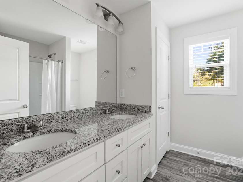 351 Center Street, Kannapolis, NC 28083.  MLS# CAR4304032, YatesRealty ID 4248. The bright primary bathroom features a luxurious double vanity with striking granite countertops, white shaker cabinets, and an abundance of natural light