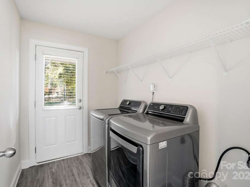 351 Center Street, Kannapolis, NC 28083.  MLS# CAR4304032, YatesRealty ID 4248. The conveniently located laundry room features modern flooring, a full-size washer and dryer, wire shelving for storage, and provides direct outdoor access through a back door