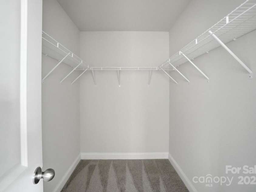351 Center Street, Kannapolis, NC 28083.  MLS# CAR4304032, YatesRealty ID 4248. The large primary walk-in closet offers ample storage space, featuring a clean layout with neutral paint and ventilated shelving installed on three sides