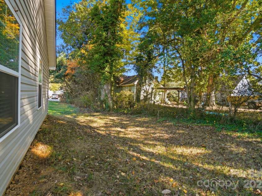 351 Center Street, Kannapolis, NC 28083.  MLS# CAR4304032, YatesRealty ID 4248. The property includes a spacious, level side yard bordered by mature trees for privacy and features a low-maintenance vinyl exterior