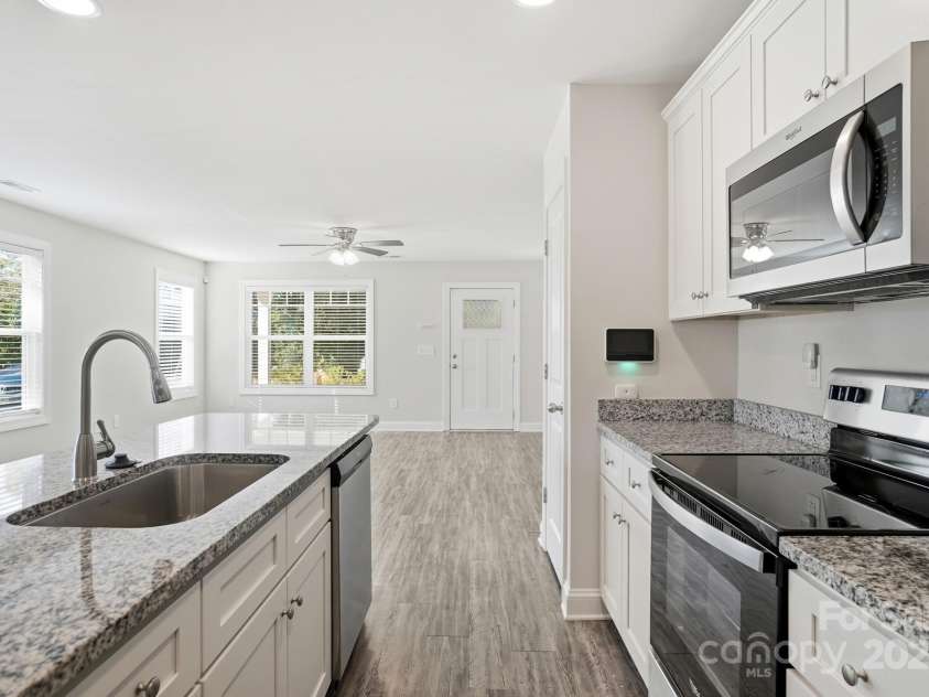 351 Center Street, Kannapolis, NC 28083.  MLS# CAR4304032, YatesRealty ID 4248. The sleek, galley-style kitchen boasts white shaker cabinets, beautiful granite countertops, and a full suite of stainless steel appliances, overlooking the bright living area along with a full-size pantry closet.