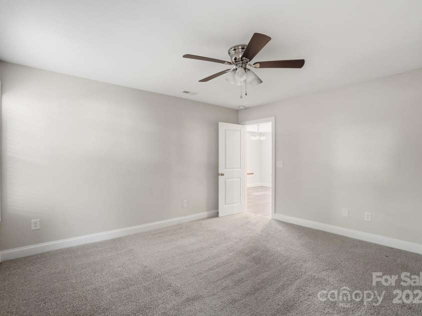 351 Center Street, Kannapolis, NC 28083.  MLS# CAR4304032, YatesRealty ID 4248. This generously sized bedroom boasts a neutral color palette, plush carpet, and a classic ceiling fan for comfort, offering a bright and ready-to-customize space
