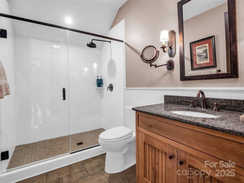 305 Clubhouse Lane, Mill Spring, NC 28756.  MLS# CAR4241690, YatesRealty ID 4258. Elegant ensuite bath featuring a sleek walk-in shower with modern glass panels, and refined finishes.