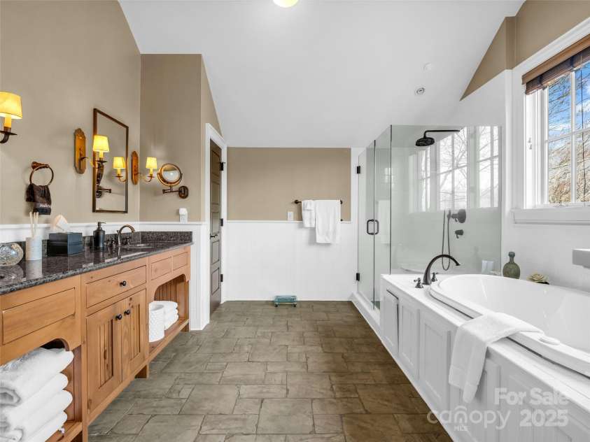 305 Clubhouse Lane, Mill Spring, NC 28756.  MLS# CAR4241690, YatesRealty ID 4258. Opulent primary bathroom featuring a spa-like atmosphere with a freestanding soaking tub, oversized walk-in shower, and dual vanities.