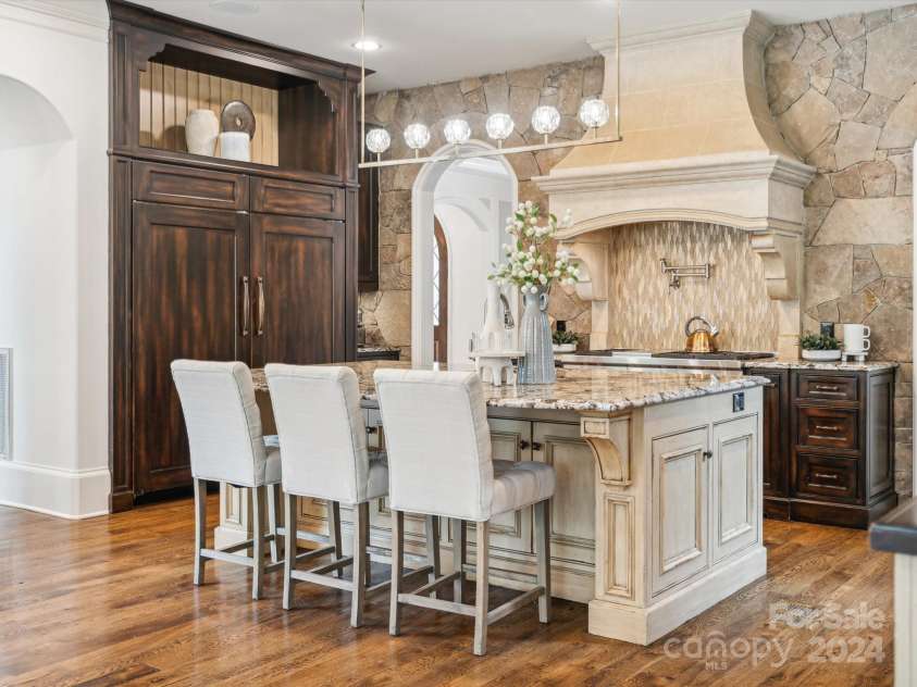 9044 Island Point Road, Charlotte, NC 28278.  MLS# CAR4135509, YatesRealty ID 428. This kitchen epitomizes unparalleled quality, featuring an expansive custom stone hood and a meticulously hand-laid stone backsplash that extends gracefully to the ceiling