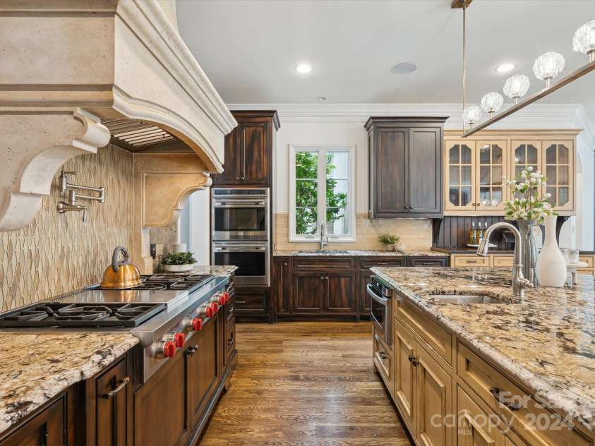 9044 Island Point Road, Charlotte, NC 28278.  MLS# CAR4135509, YatesRealty ID 428. This kitchen epitomizes unparalleled quality, featuring an expansive custom stone hood and a meticulously hand-laid stone backsplash that extends gracefully to the ceiling