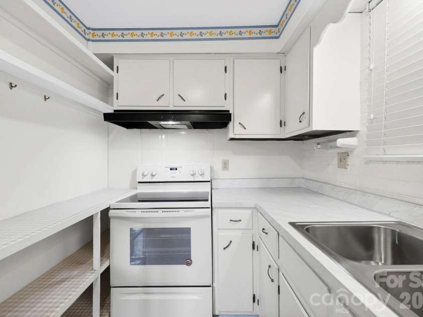 4295 Brevard Road, Horse Shoe, NC 28742.  MLS# CAR4413220, YatesRealty ID 42810. An additional view highlightsthe kitchen’s generous counterspace, built-in open shelving,electric range, and abundantcabinet storage.